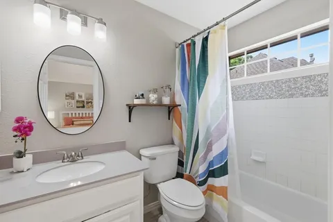 a bathroom with a granite countertop toilet a sink and a mirror
