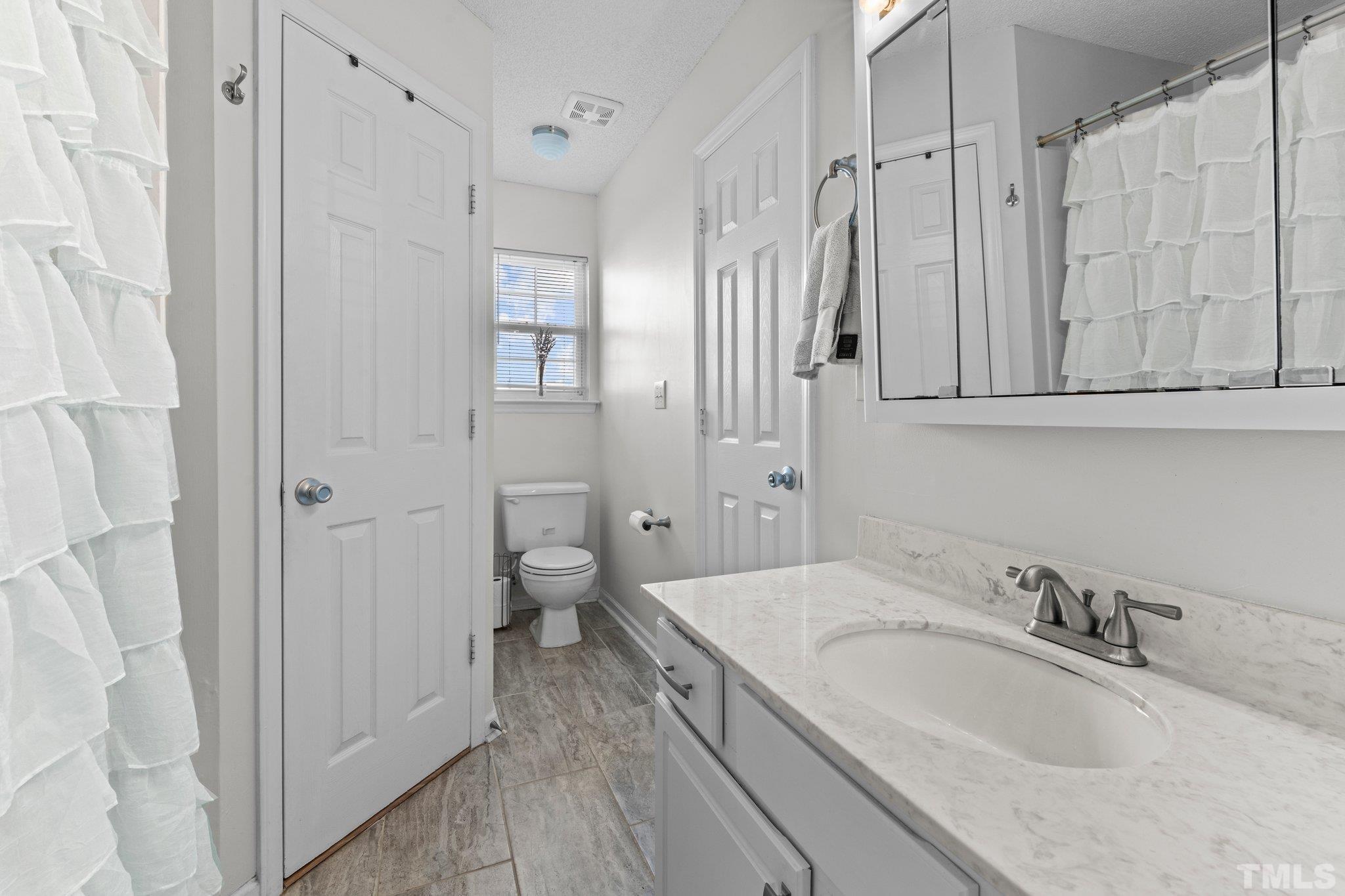 506 Ashford Lane Durham, NC 27713 - Photo 11 of 27 a bathroom with a granite countertop sink a mirror and a bathtub