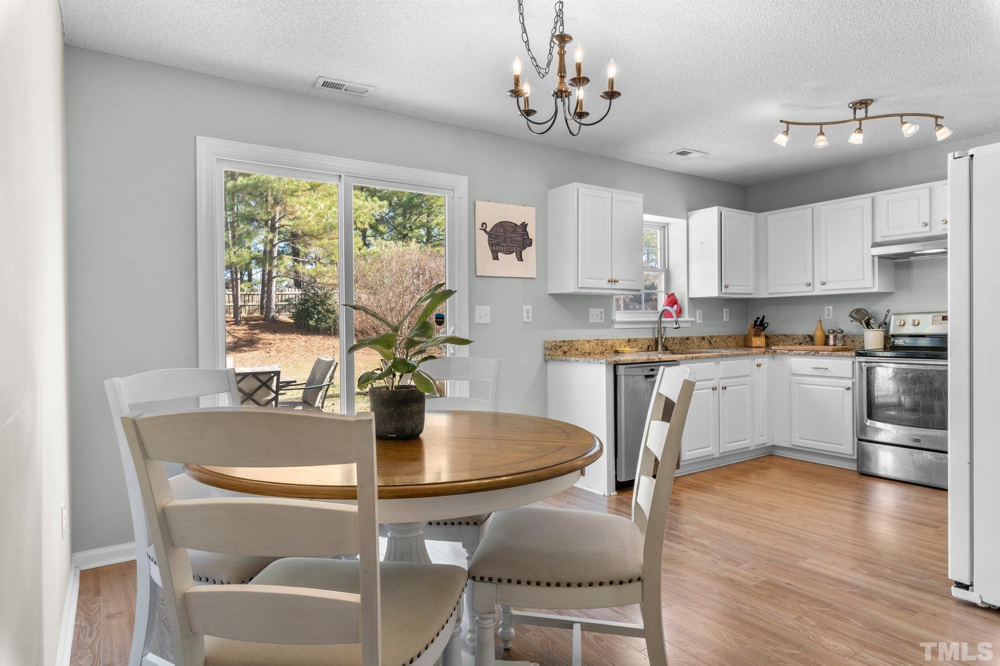506 Ashford Lane Durham, NC 27713 - Photo 5 of 27 a kitchen with stainless steel appliances granite countertop a stove top oven a refrigerator a dining table and chairs with wooden floor