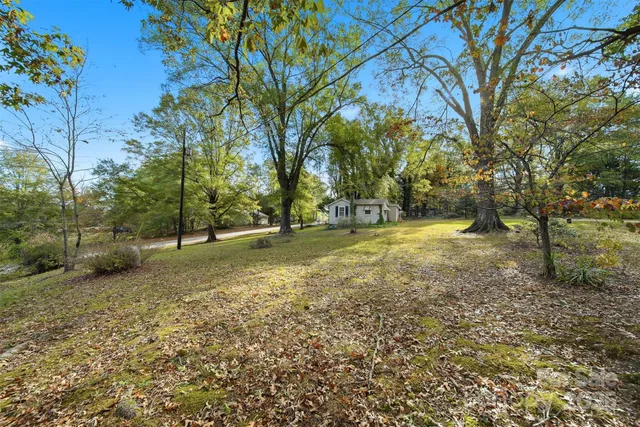 a view of swimming pool with lawn chairs and large trees