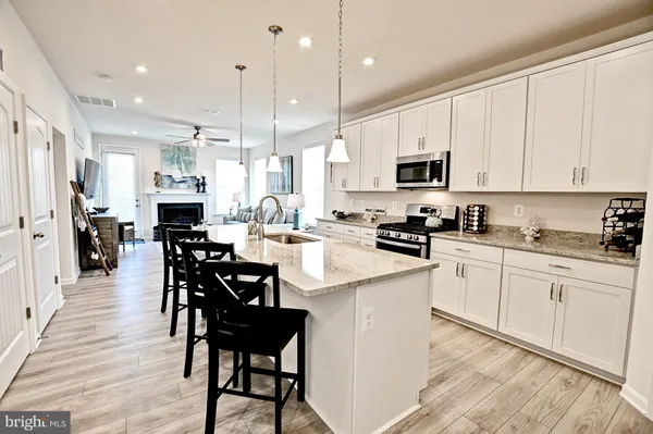 a kitchen with stainless steel appliances kitchen island granite countertop a table chairs and a cabinets