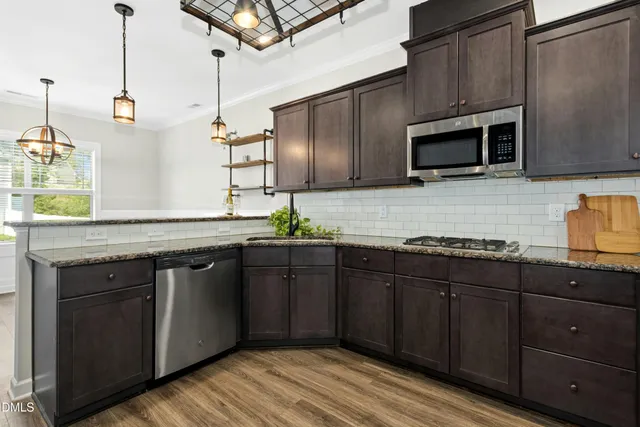 a kitchen with stainless steel appliances granite countertop a sink a stove and wooden cabinets