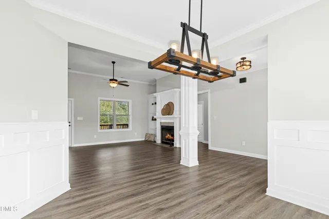 a view of a livingroom with wooden floor a ceiling fan and windows