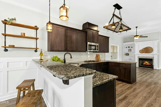 a kitchen with stainless steel appliances granite countertop a sink a stove and a wooden floors
