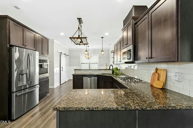 a kitchen with granite countertop a sink a counter space stainless steel appliances and cabinets