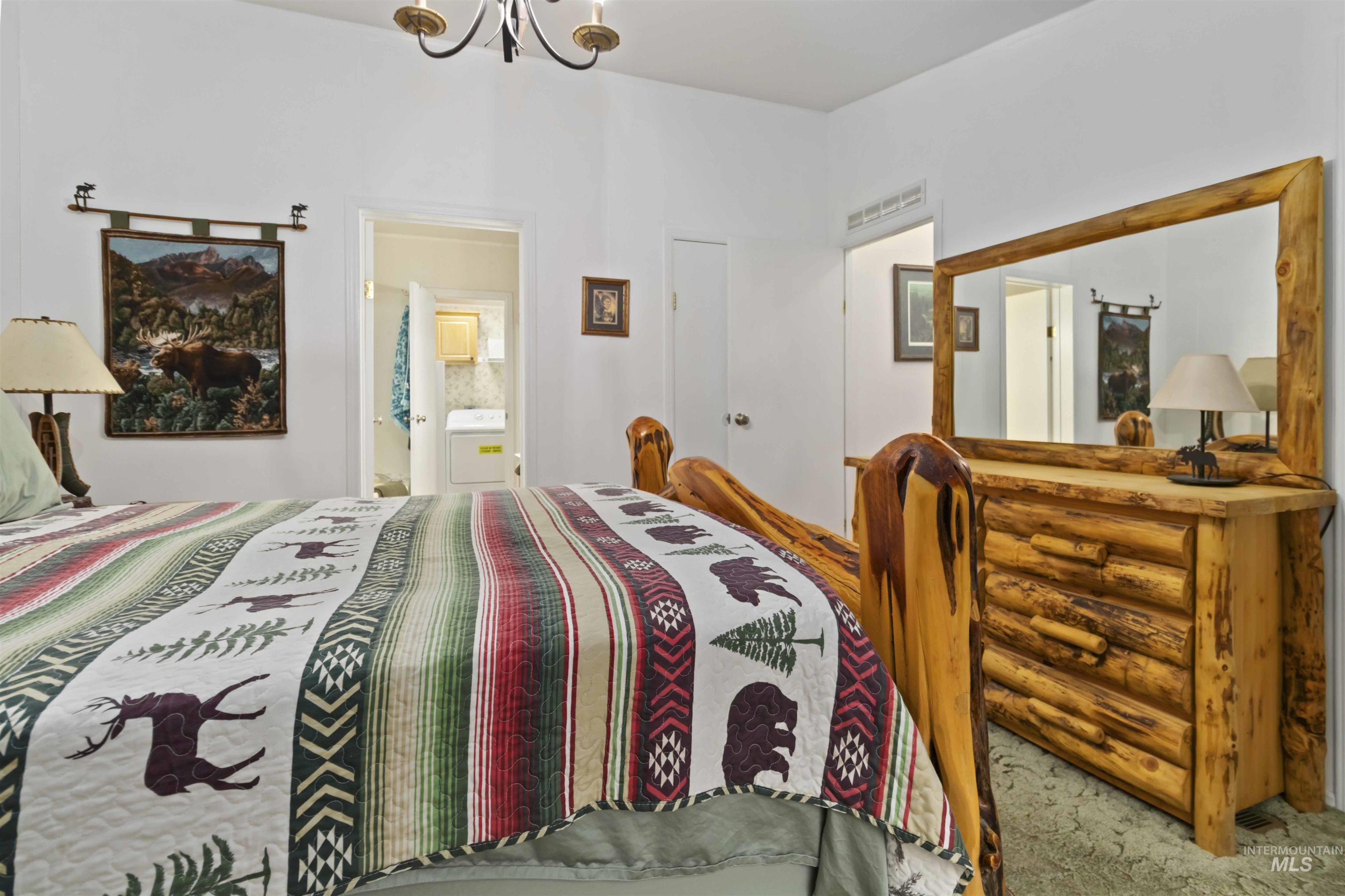 9592 Packer John Road Cascade, ID 83611 - Photo 25 of 47 Carpeted bedroom with ensuite bathroom, a chandelier, and washer / clothes dryer