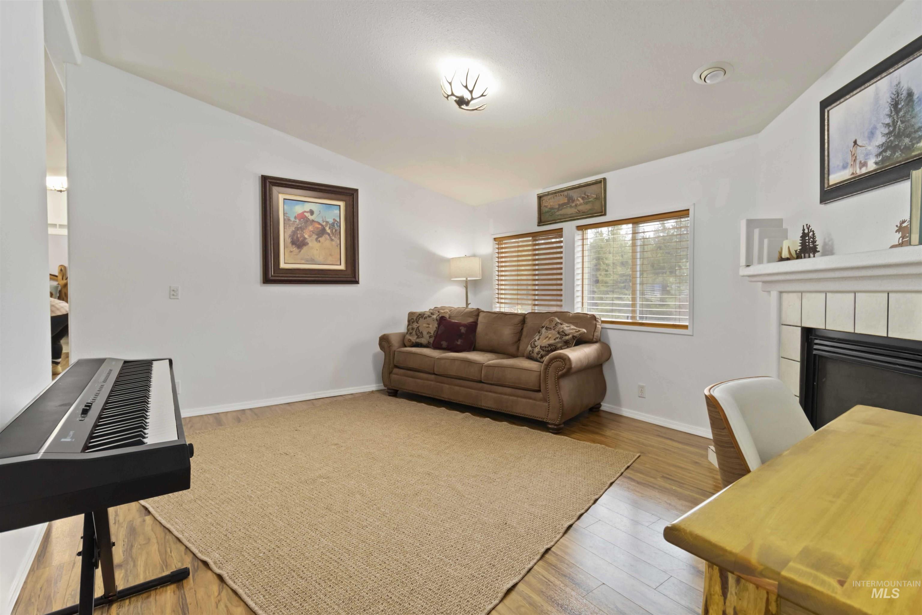 9592 Packer John Road Cascade, ID 83611 - Photo 31 of 47 Living area featuring vaulted ceiling, a tiled fireplace, and light wood-type flooring