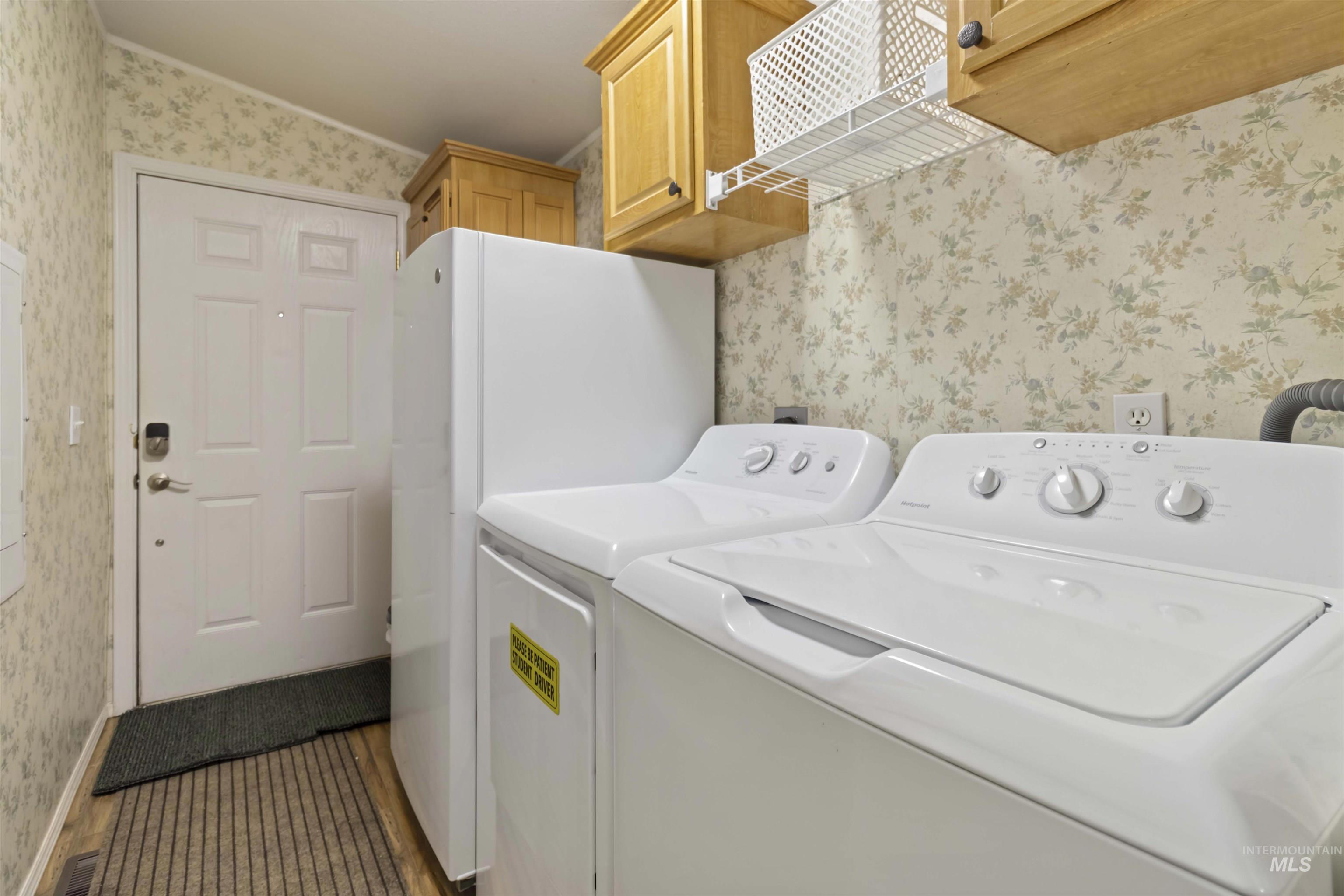 9592 Packer John Road Cascade, ID 83611 - Photo 6 of 47 Washroom featuring wallpapered walls, cabinet space, washing machine and dryer, and light wood-style flooring