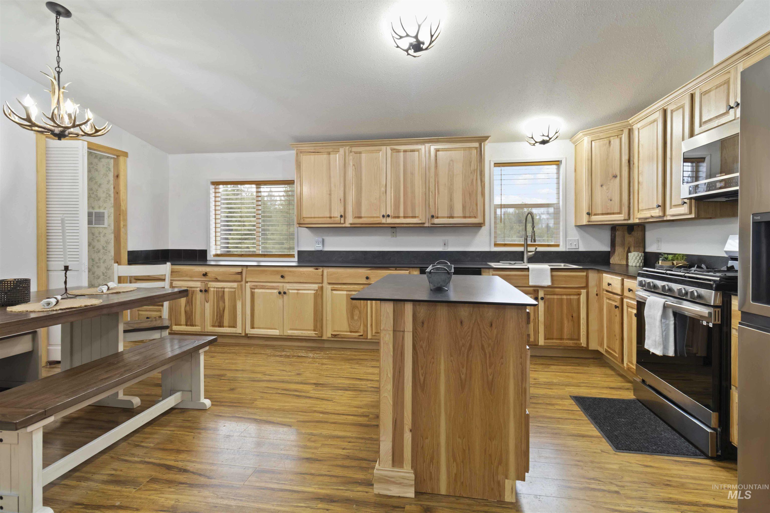 9592 Packer John Road Cascade, ID 83611 - Photo 8 of 47 Kitchen with appliances with stainless steel finishes, a chandelier, dark countertops, light wood-type flooring, and vaulted ceiling