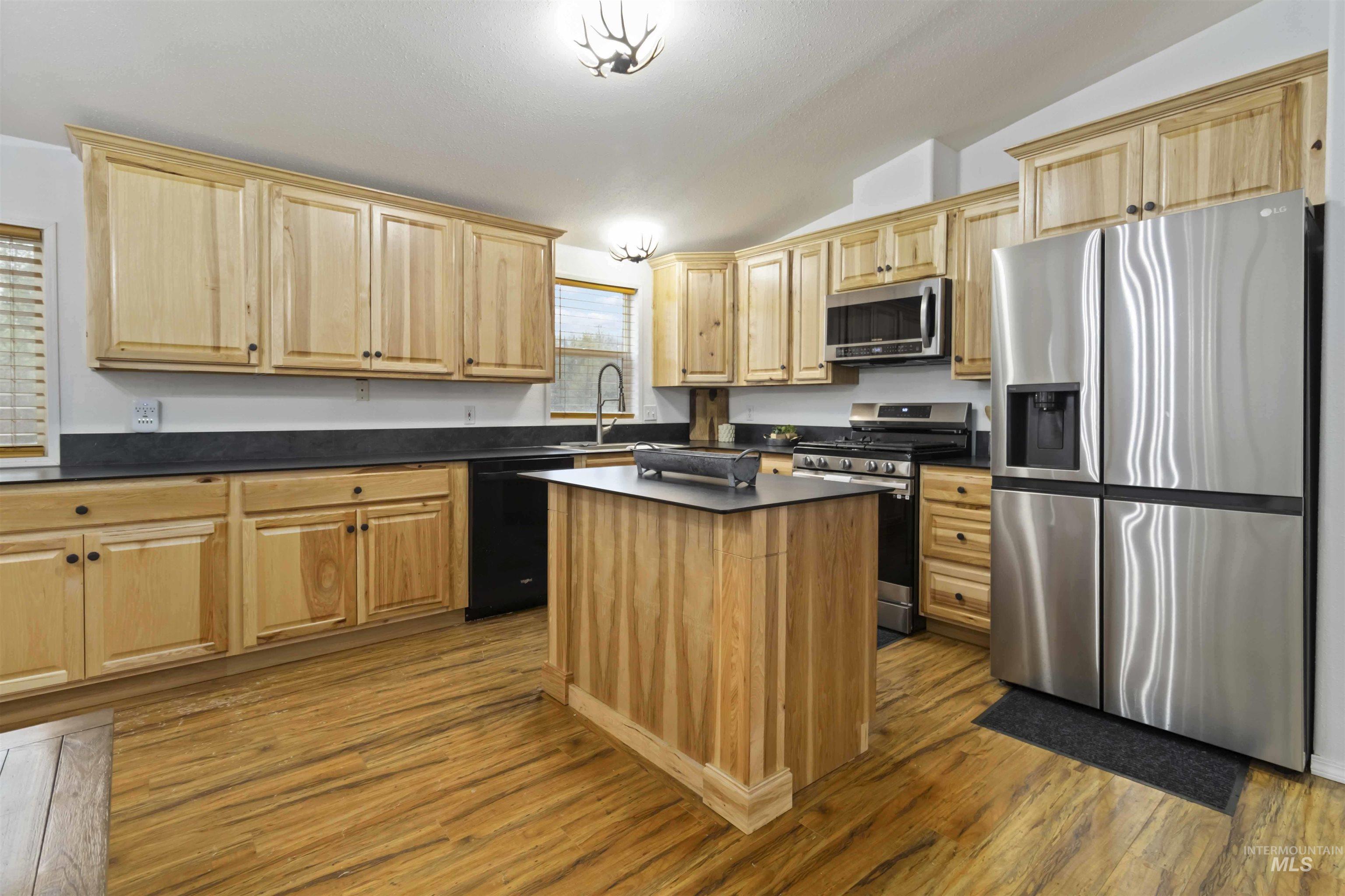 9592 Packer John Road Cascade, ID 83611 - Photo 9 of 47 Kitchen featuring stainless steel appliances, dark countertops, vaulted ceiling, dark wood-style floors, and a kitchen island