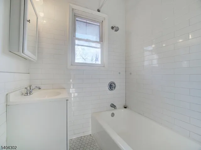 a bathroom with a tub sink and mirror