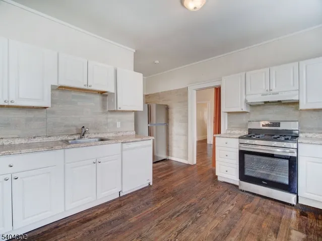 a kitchen with granite countertop white cabinets and stainless steel appliances