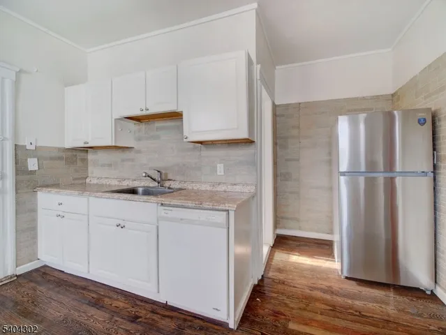 a kitchen with granite countertop a sink and a refrigerator