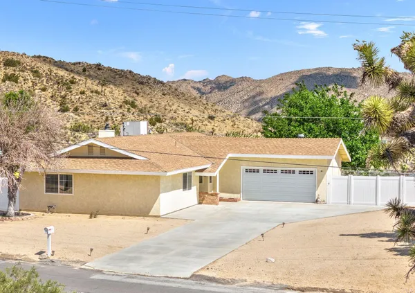 a front view of a house with a yard and mountain view in back