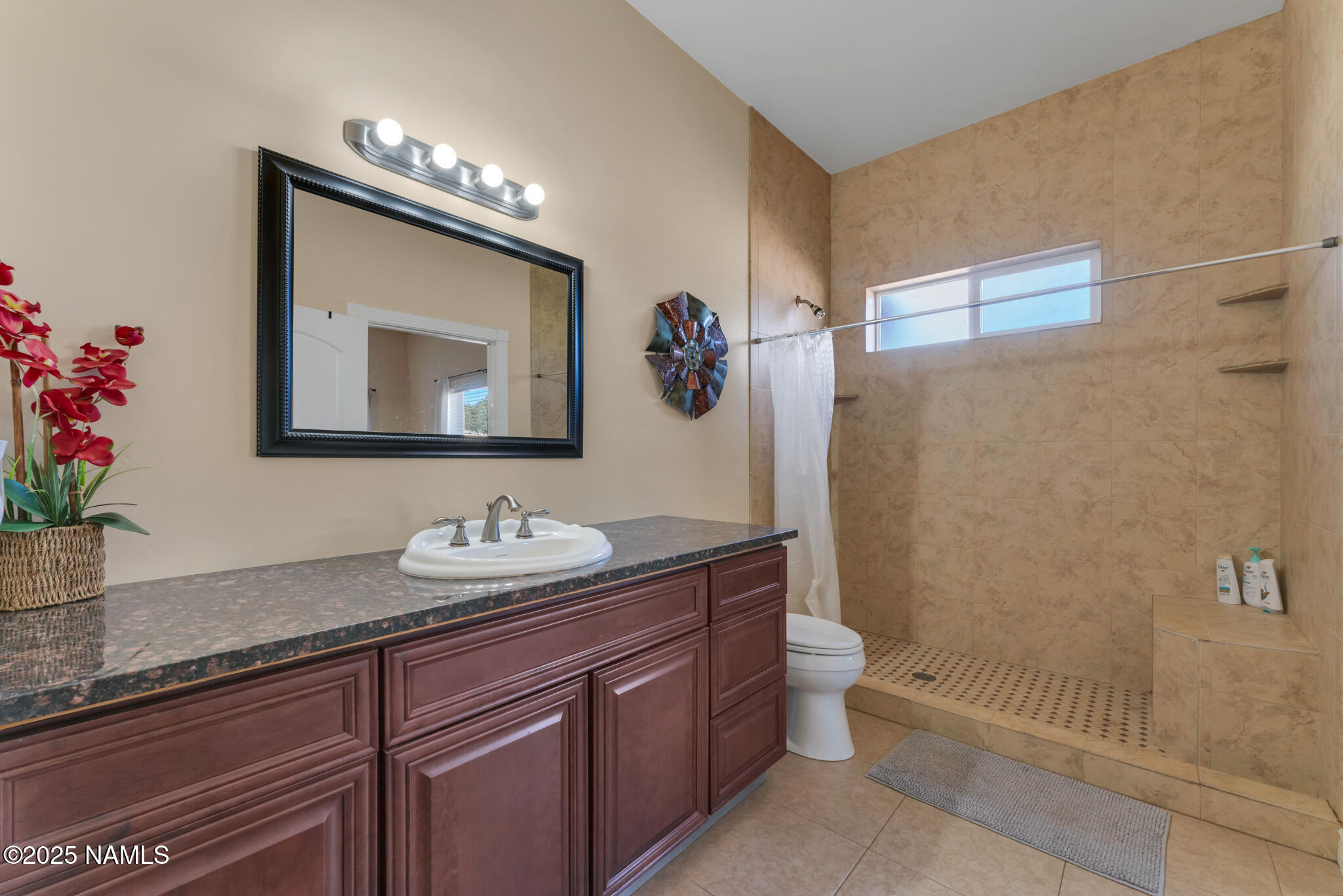 8752 South Lariat Road Williams, AZ 86046 - Photo 16 of 38 a bathroom with a granite countertop sink a toilet a mirror and shower