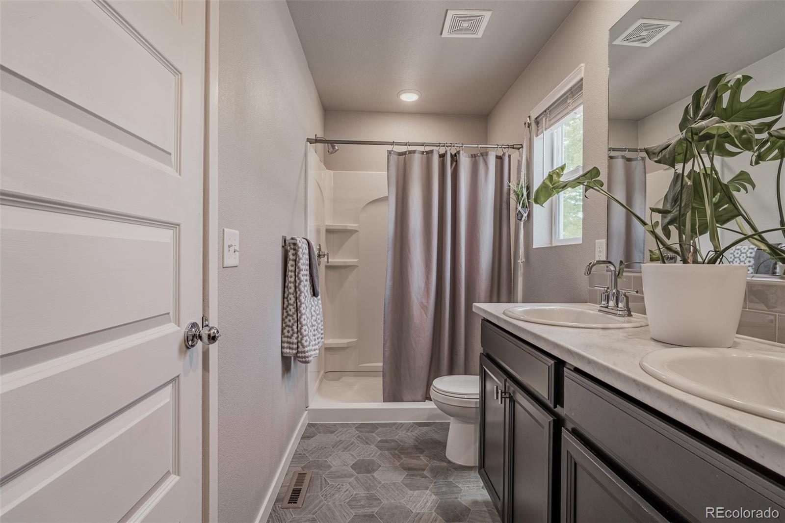 3301 Sandy Harbor Drive Evans, CO 80620 - Photo 18 of 27 a bathroom with a granite countertop sink a mirror and a shower