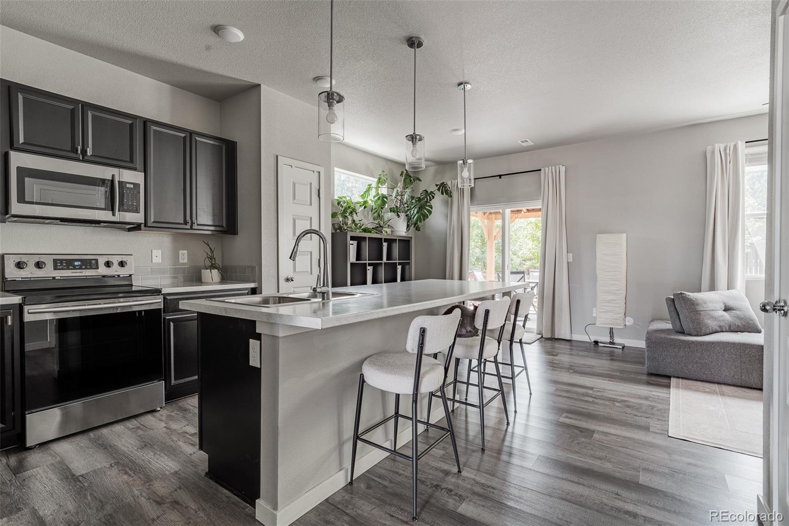 3301 Sandy Harbor Drive Evans, CO 80620 - Photo 7 of 27 a kitchen with stainless steel appliances granite countertop a stove top oven a sink dishwasher a dining table and chairs with wooden floor
