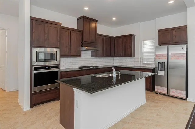 a kitchen with kitchen island granite countertop a sink stove and refrigerator