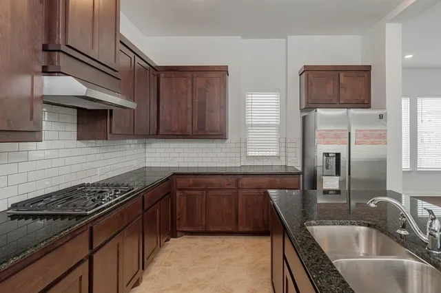 a kitchen that has a sink wooden cabinets and stainless steel appliances