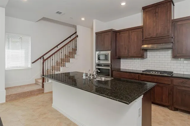 a kitchen with kitchen island granite countertop a sink a stove and cabinets