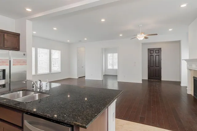a kitchen with stainless steel appliances granite countertop a sink a large window and wooden floor