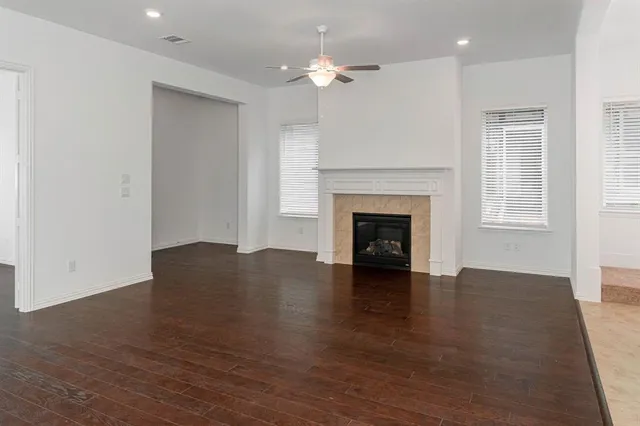 a view of an empty room with wooden floor fireplace and a window