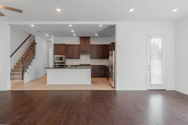 a large kitchen with stainless steel appliances kitchen island granite countertop a stove a refrigerator and a view of living room