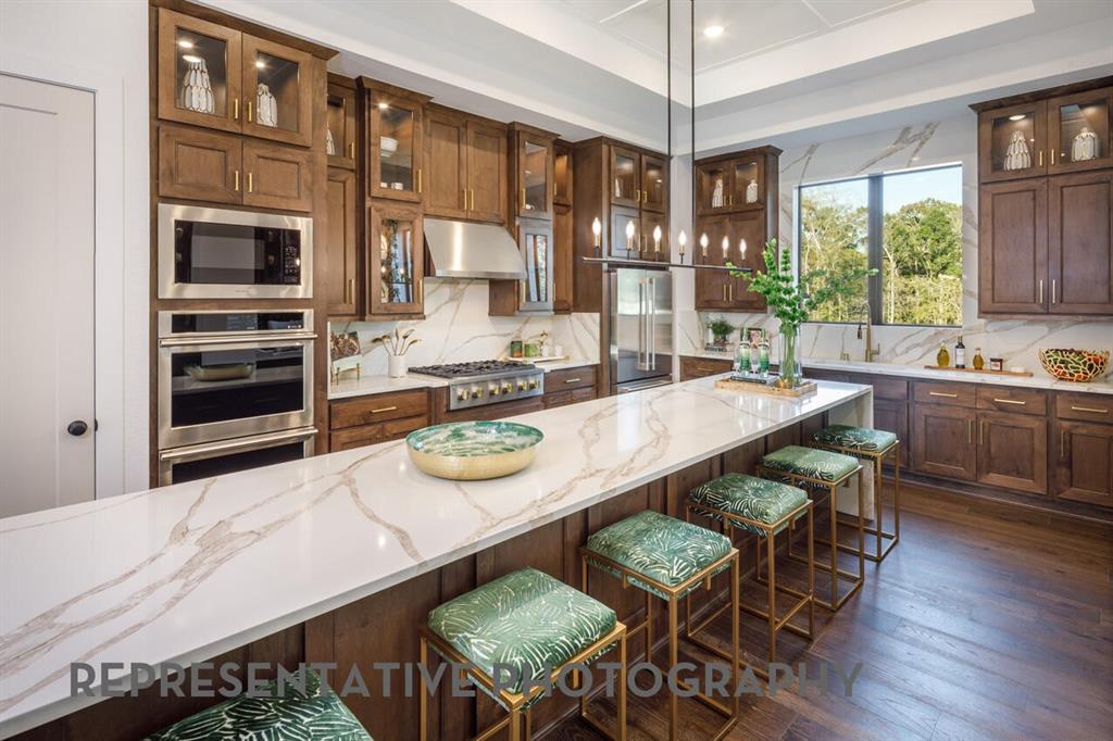 3625 Meander Way Prosper, TX 75078 - Photo 10 of 40 a kitchen with stainless steel appliances kitchen island granite countertop a table chairs sink and cabinets