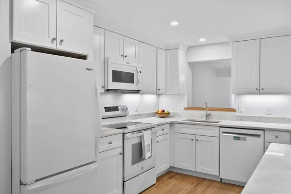 a kitchen with white cabinets sink and white appliances