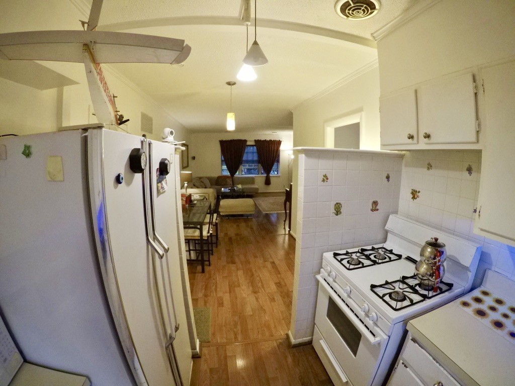 210 Lake Shore Road, Unit 3 Boston, MA 02135 - Photo 6 of 20 a kitchen with stainless steel appliances granite countertop a refrigerator a stove and a sink with wooden floor