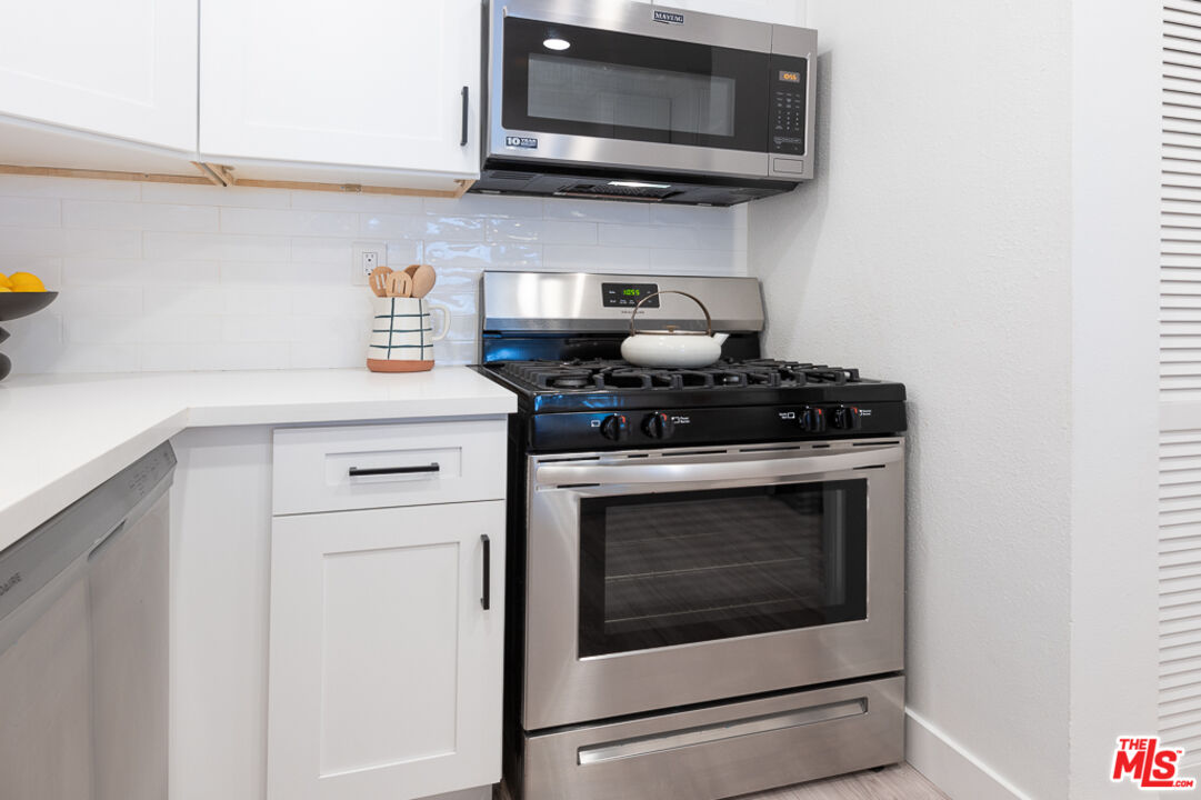 839 Larrabee Street, Unit 6 West Hollywood, CA 90069 - Photo 19 of 34 a kitchen with stainless steel appliances granite countertop white cabinets a microwave a stove and a refrigerator