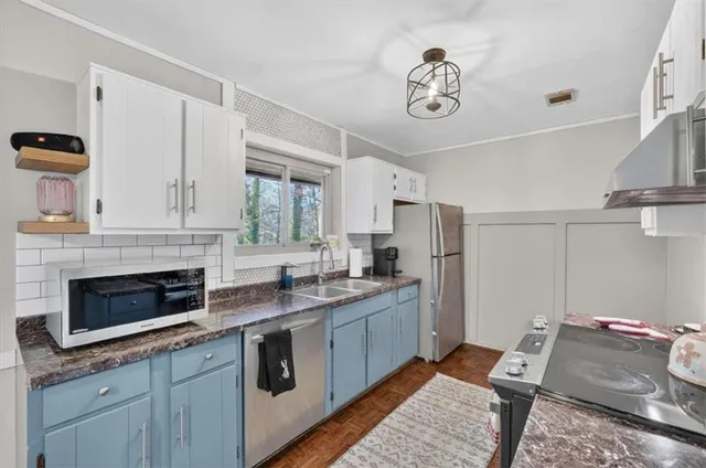 a kitchen with stainless steel appliances granite countertop a stove a sink and a refrigerator with white cabinets