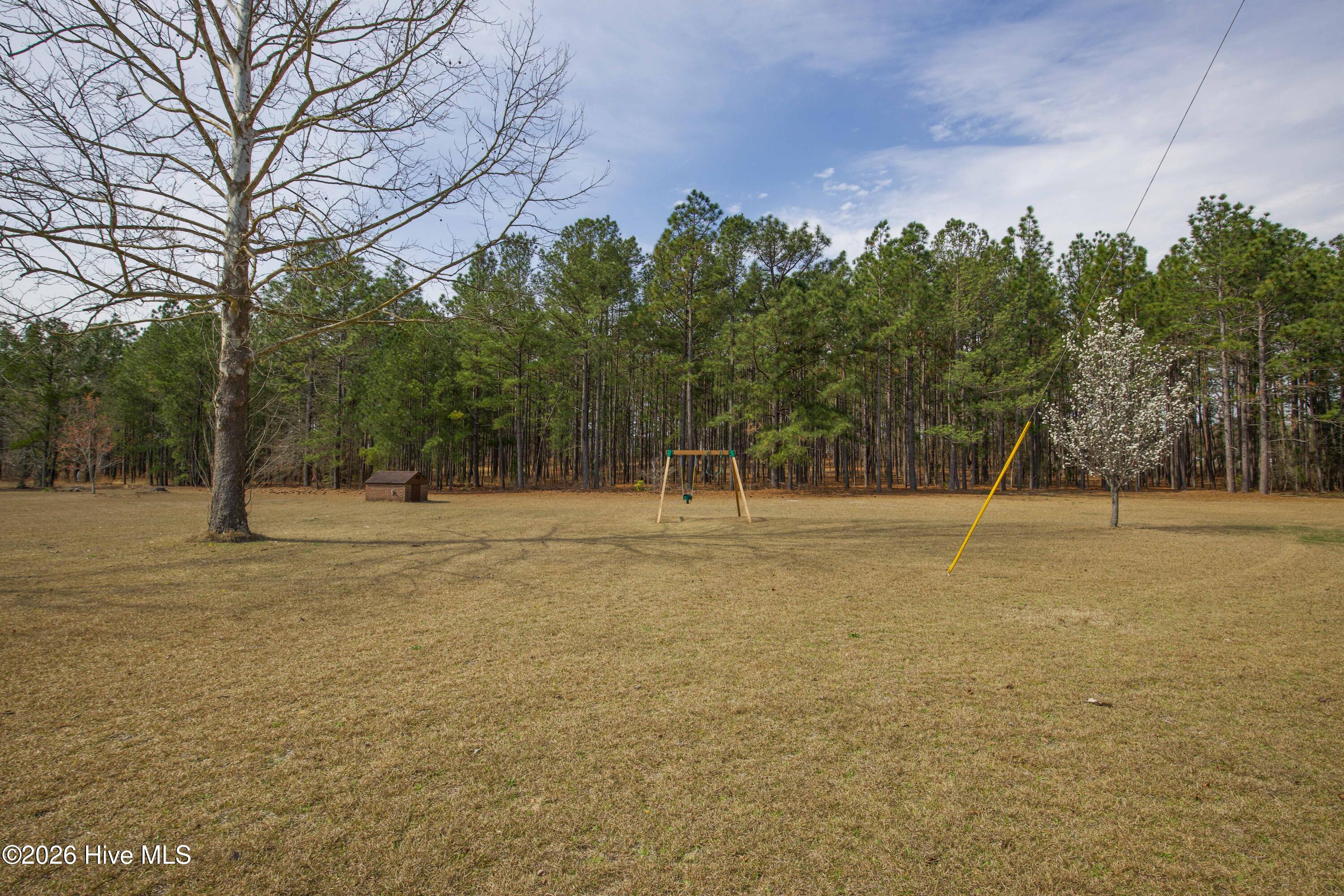 124 Joseph Road Aberdeen, NC 28315 - Photo 12 of 64 View across the open yard and surrounding acreage at 124 Joseph Road. The approximately 5.06 acre property features a mix of open lawn and mature trees, providing space for outdoor activities, gardening, or future improvements. The expansive land offers a quiet Moore County setting while remaining conveniently located near Aberdeen, Southern Pines, Pinehurst, and commuter routes to Fort Bragg and Camp Mackall.