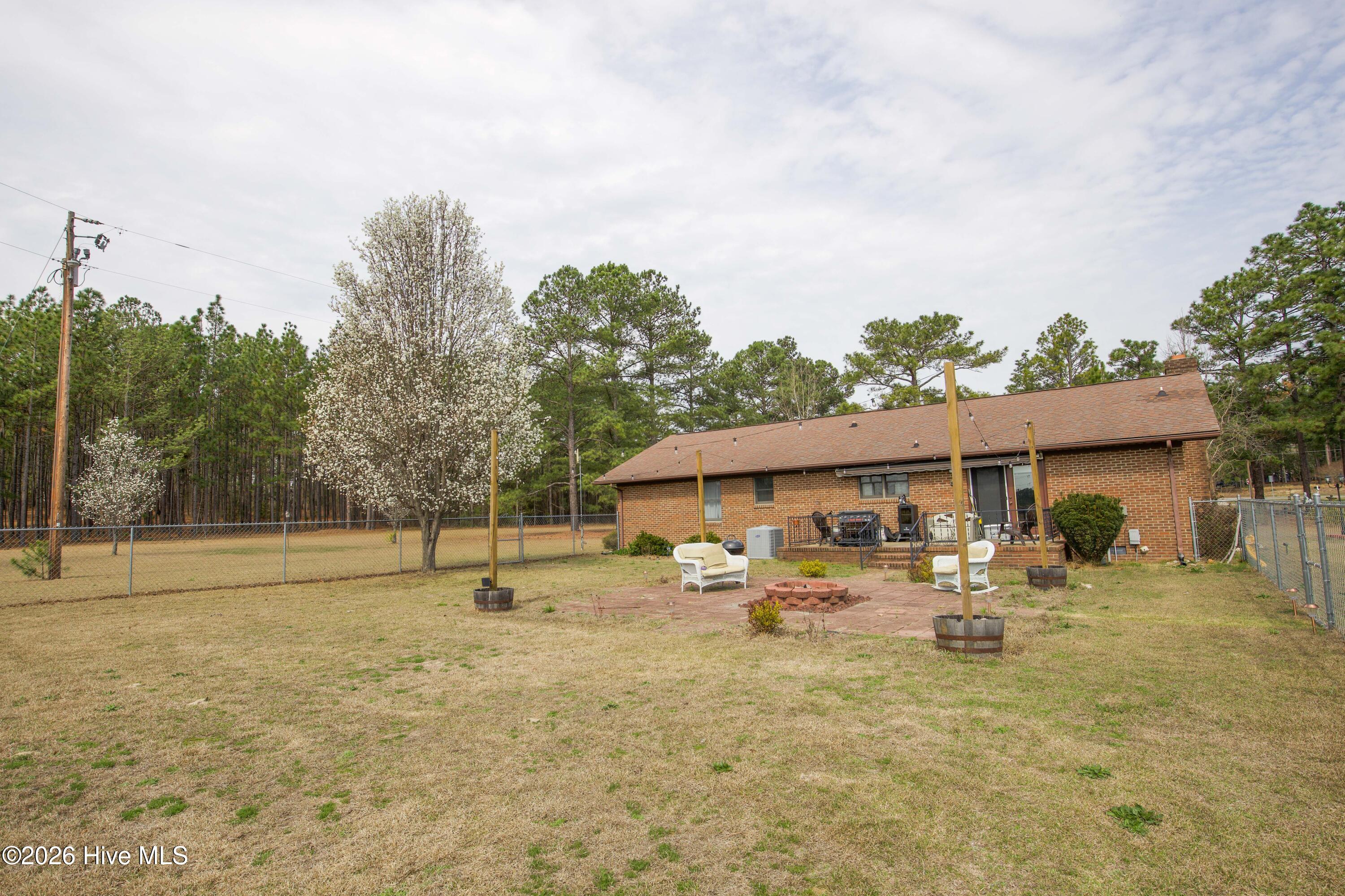 124 Joseph Road Aberdeen, NC 28315 - Photo 19 of 64 View of the backyard and outdoor gathering area behind the home at 124 Joseph Road. The open yard and seating area provide a comfortable space for relaxing or entertaining while enjoying the privacy of approximately 5.06 acres in Moore County. The property offers a combination of open lawn and mature trees with room for gardening, recreation, or future improvements.