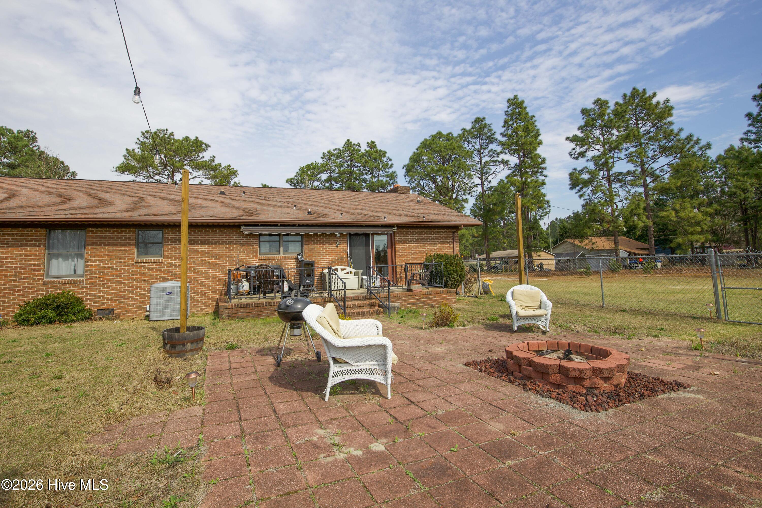 124 Joseph Road Aberdeen, NC 28315 - Photo 21 of 64 Backyard patio area at 124 Joseph Road featuring a firepit and outdoor seating space ideal for relaxing or entertaining. The patio overlooks the open yard and surrounding acreage, providing a peaceful setting for outdoor living. The approximately 5.06 acre property offers room for gardening, recreation, or additional outdoor improvements.