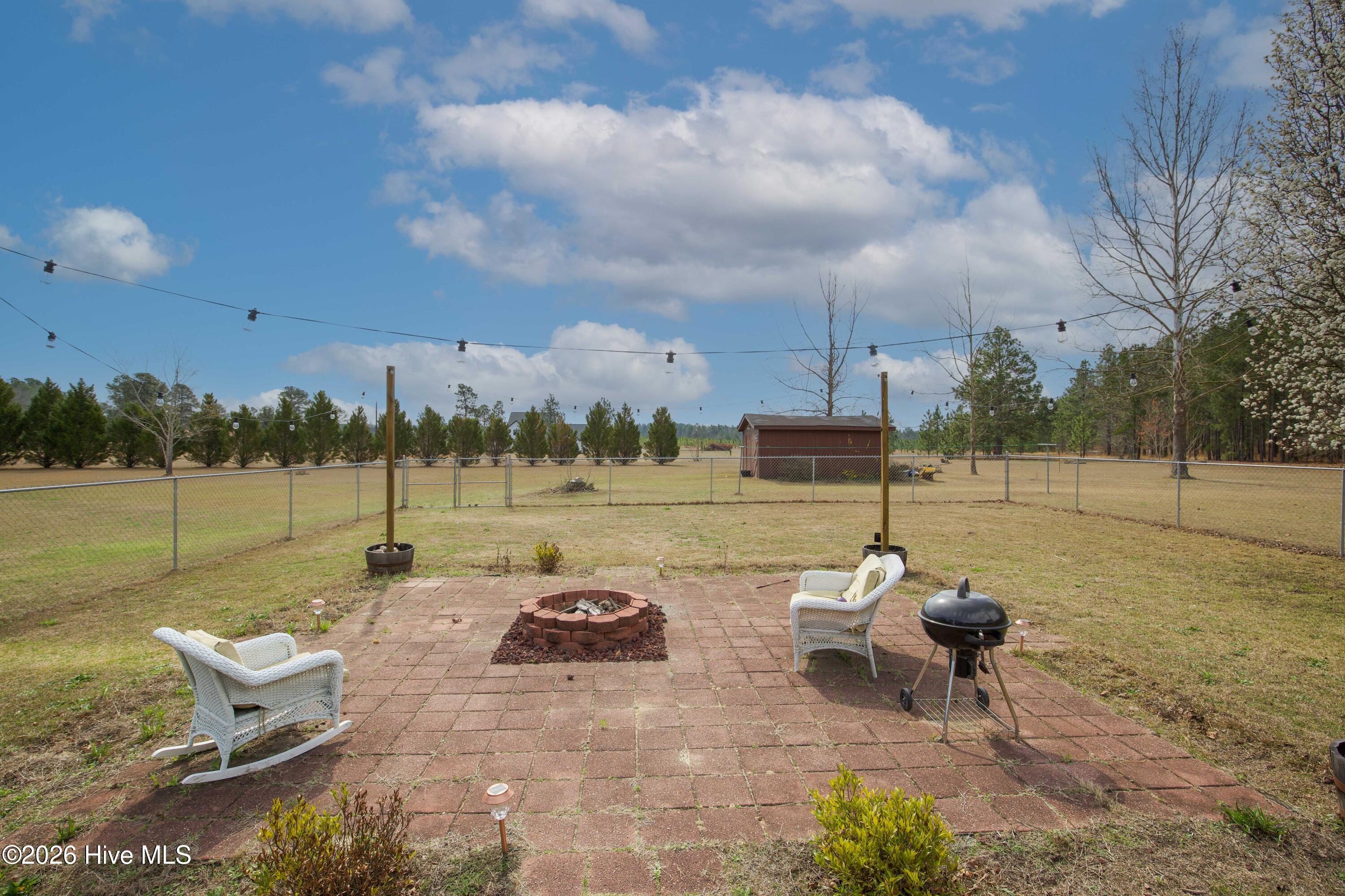 124 Joseph Road Aberdeen, NC 28315 - Photo 22 of 64 View from the backyard patio looking across the open yard and surrounding acreage at 124 Joseph Road. The property offers approximately 5.06 acres with a blend of lawn and mature trees that provide space for outdoor activities and a private rural setting.