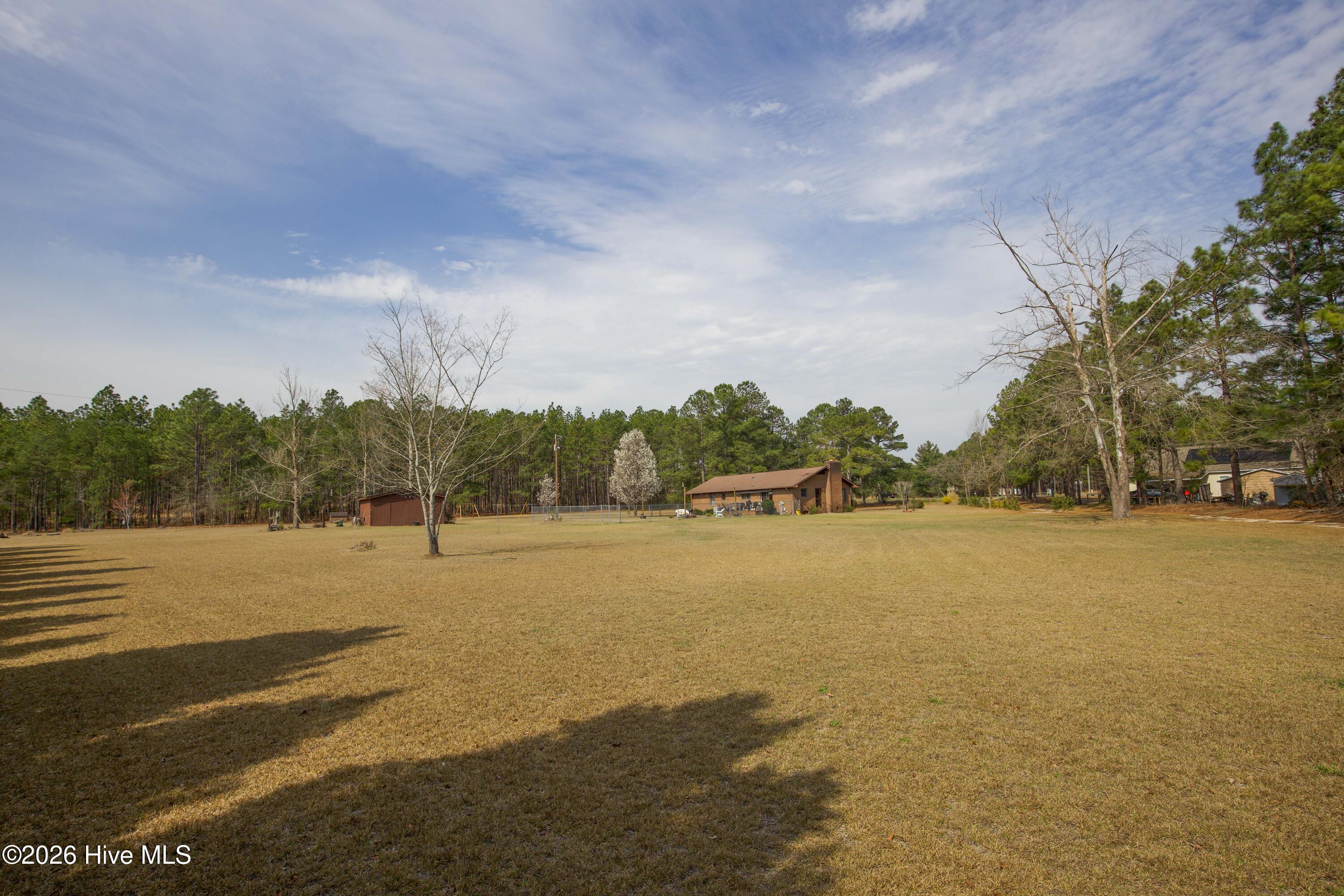 124 Joseph Road Aberdeen, NC 28315 - Photo 25 of 64 Wide view of the open yard and surrounding acreage at 124 Joseph Road. The property features approximately 5.06 acres with a combination of open lawn and mature trees, offering privacy and flexibility for outdoor activities, gardening, or future improvements