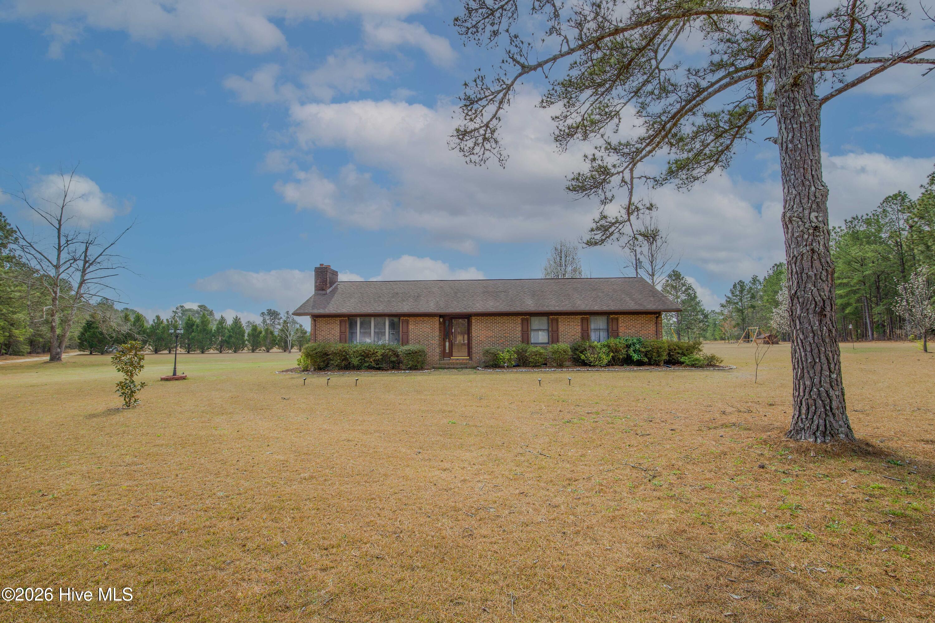 124 Joseph Road Aberdeen, NC 28315 - Photo 2 of 64 Front yard view of the brick ranch home at 124 Joseph Road situated on approximately 5.06 acres in Moore County. The property features a large open lawn, mature trees, and a quiet rural setting with room for outdoor activities, gardening, or additional improvements, while remaining close to Aberdeen, Southern Pines, Pinehurst, and commuter routes to Fort Bragg and Camp Mackall.
