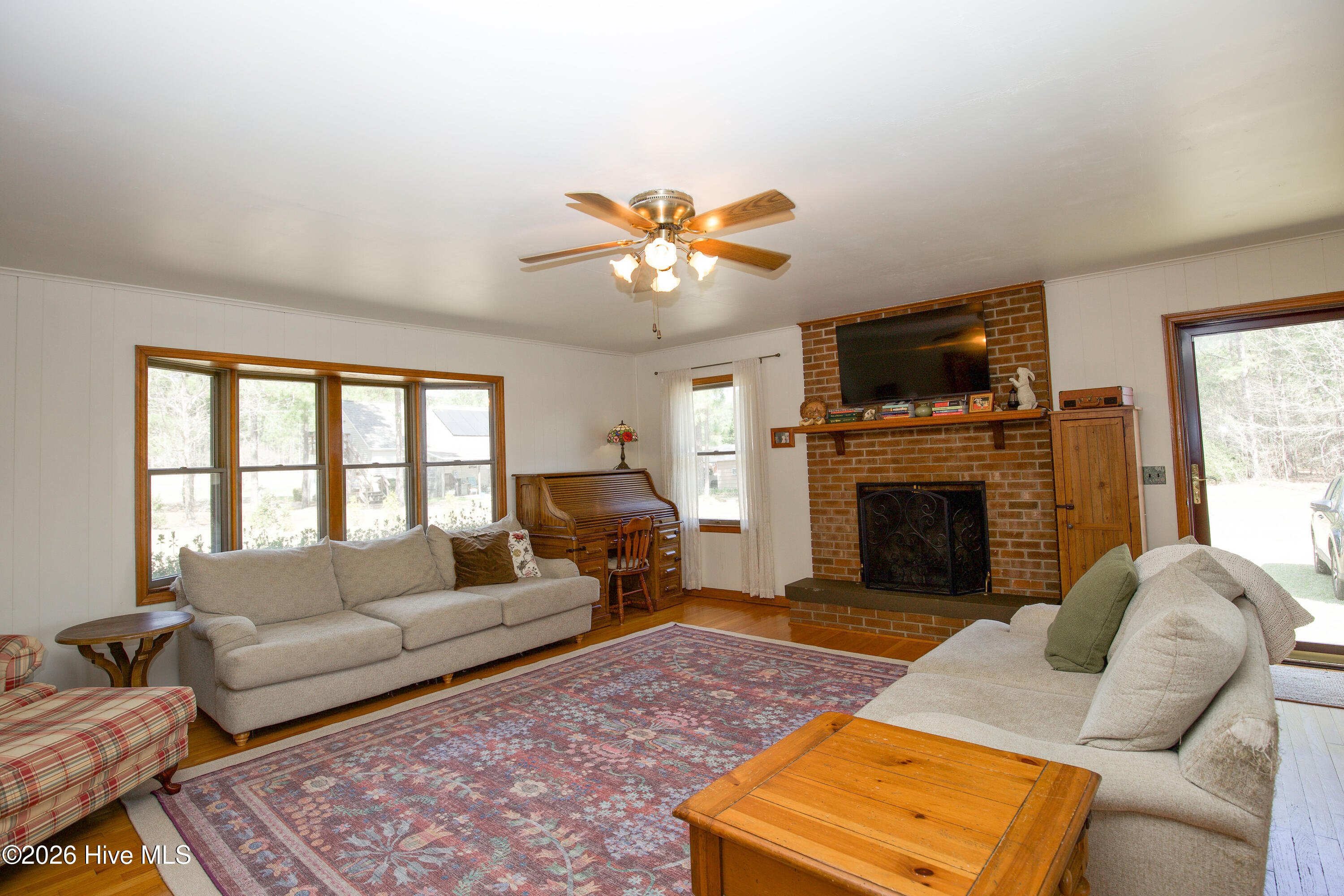124 Joseph Road Aberdeen, NC 28315 - Photo 7 of 59 Living room view featuring front-facing windows, fireplace, and warm natural lighting throughout the space.