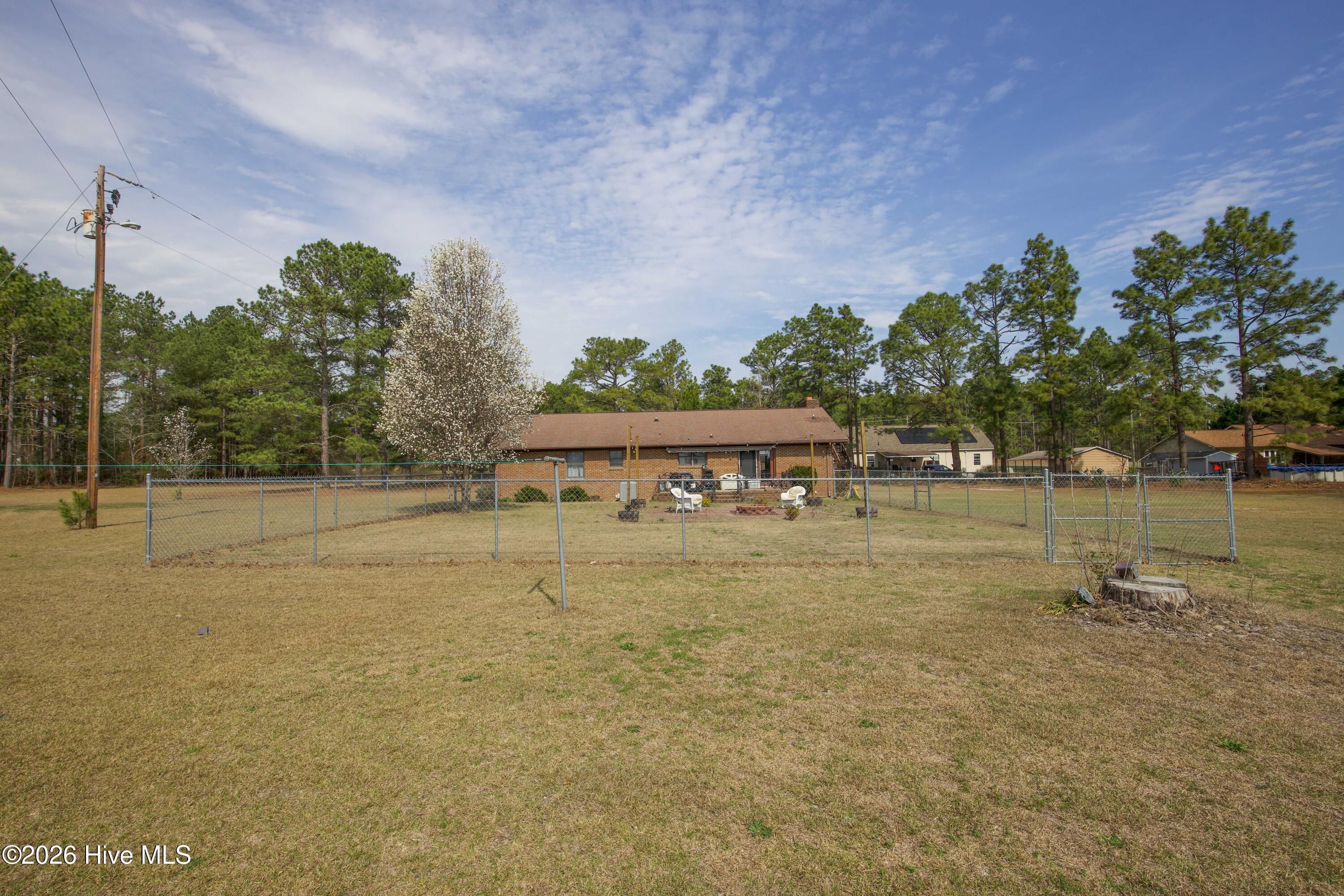 124 Joseph Road Aberdeen, NC 28315 - Photo 8 of 64 View of the backyard at 124 Joseph Road showing the fenced area behind the home and surrounding open yard space. The property sits on approximately 5.06 acres in Moore County and offers a combination of lawn and mature trees that provide privacy and usable outdoor space. The fenced portion of the yard offers flexibility for pets, gardening, or outdoor recreation while enjoying the peaceful rural setting.