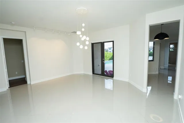 an empty room with chandelier fan and windows