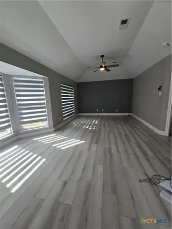 an empty room with wooden floor and windows