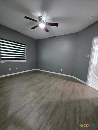a view of an empty room with wooden floor and a window