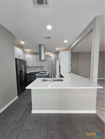 a large kitchen with stainless steel appliances a refrigerator and a counter top space