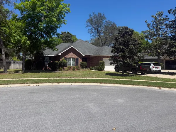 a view of house with a big yard and large trees