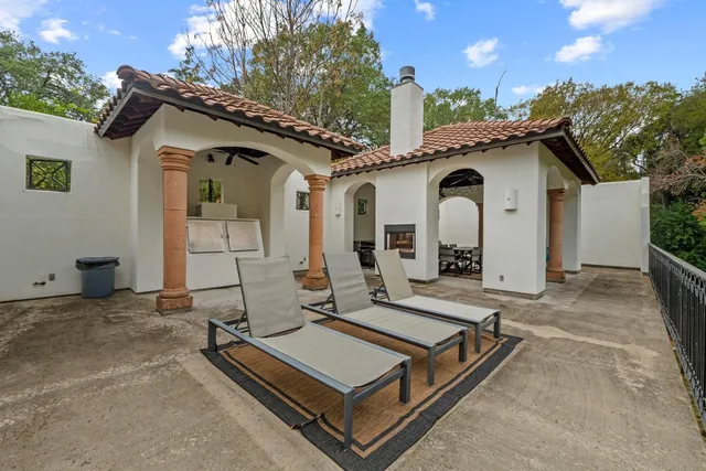 a view of a white house with a large window and potted plants