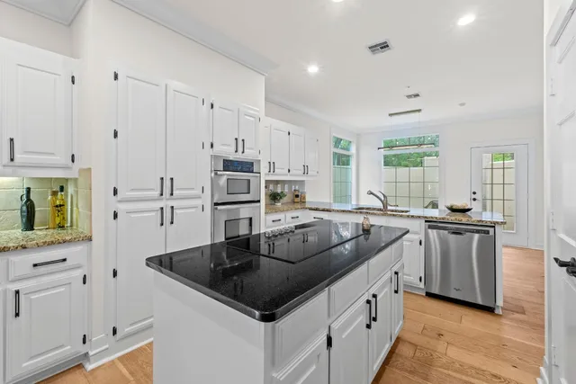 a kitchen with stainless steel appliances granite countertop a sink and white cabinets
