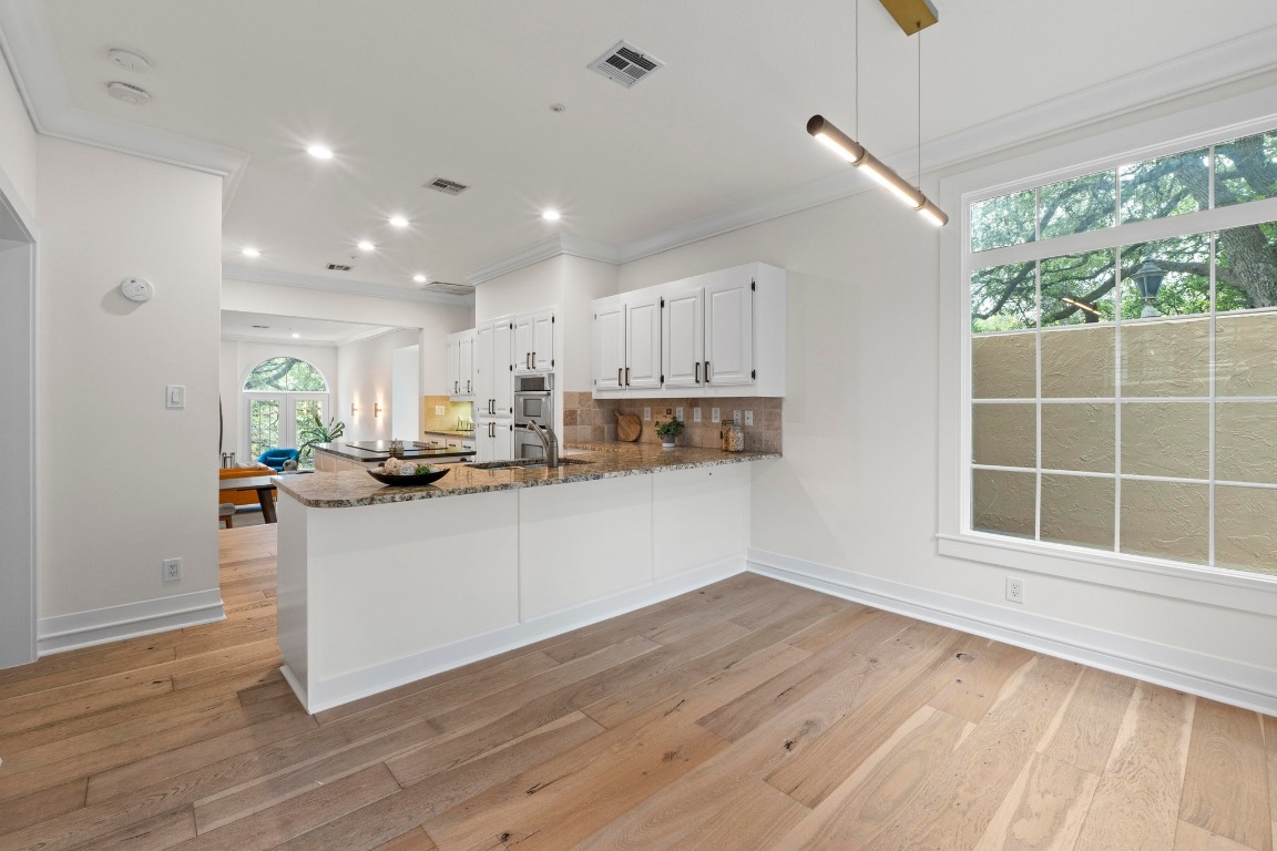1937 Rue De St Tropez, Unit 5 Austin, TX 78746 - Photo 7 of 36 a kitchen with stainless steel appliances granite countertop a refrigerator a sink dishwasher a stove and white countertops with wooden floor