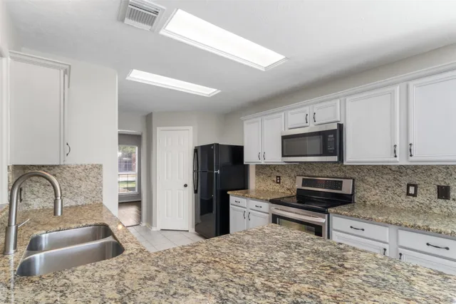 a kitchen with stainless steel appliances granite countertop a sink stove refrigerator and granite counter tops