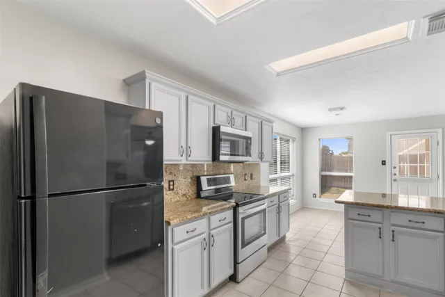 a kitchen with stainless steel appliances granite countertop a refrigerator stove microwave and sink